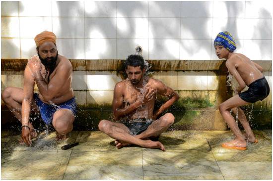 在印度阿姆利则一个公共洗浴区降温的人们