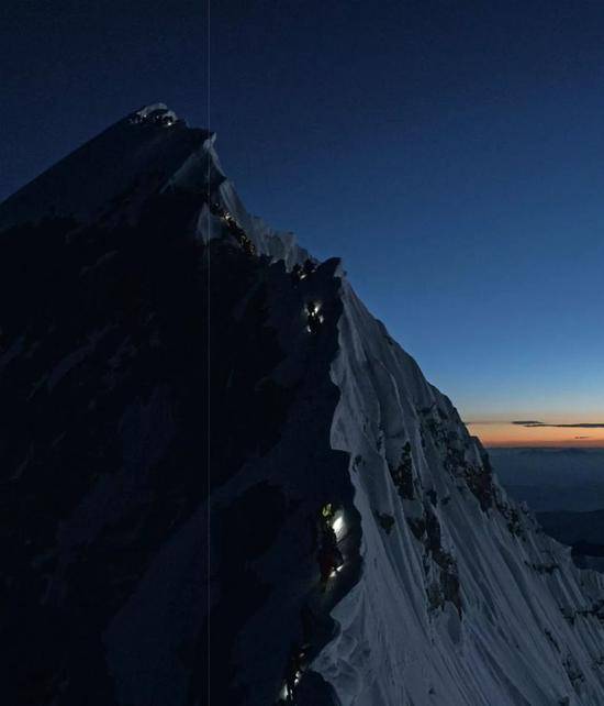 5月22日，许多登山者行过8700米接近希拉里台阶的地方，在队伍的前方，头灯点点处，已经有人登顶。摄影/Rocker