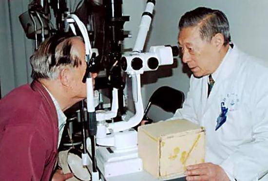 张效房（右）在为患者进行眼部检查（资料照片）。新华社发