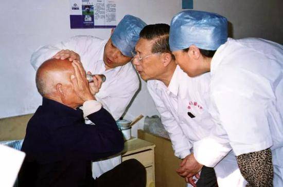 张效房（右二）在为患者进行眼部检查（资料照片）。新华社发