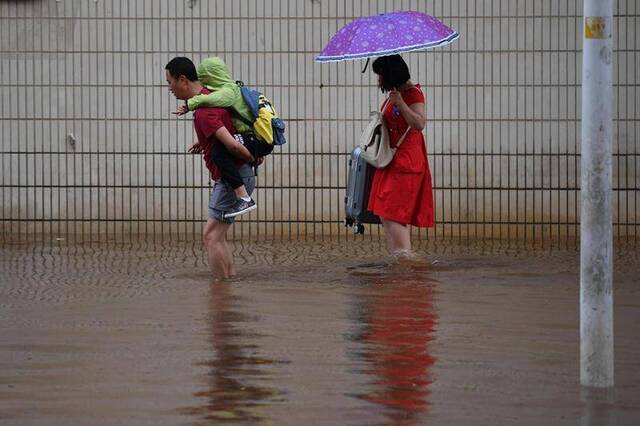  2019年7月20日，昆明，市民小心走过积水路段。视觉中国图