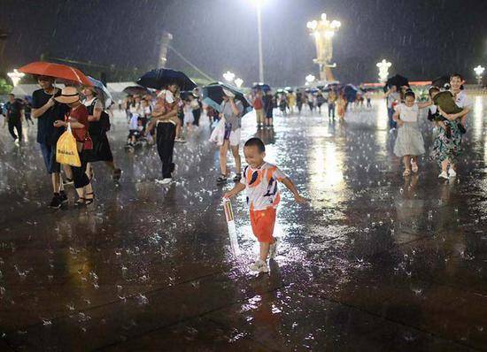 天安门广场，小朋友在大雨中蹚水享受清凉。