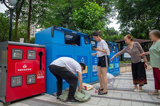 2019年7月3日，重庆市九龙坡区二郎街道钢球小区的垃圾分类智能收集箱前，一位居民正在将分类好的生活垃圾放入收集箱内。视觉中国资料