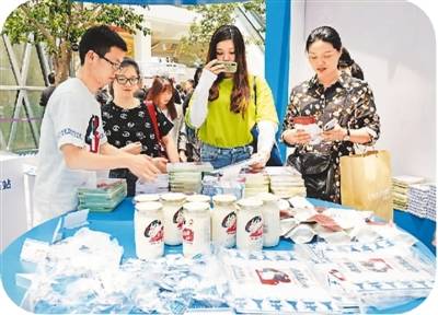 不久前，“大白兔”60周年快闪店亮相上海凯德晶萃广场，吸引了不少市民游客前来打卡。快闪店不仅提供多种口味的大白兔奶茶，现场还有抱枕、香水、环保袋、文件夹等多款文创产品出售。图为消费者在挑选商品。王初摄（人民视觉）