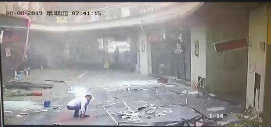 监控视频显示，爆炸后，画面中闲聊的人员受波及受伤蹲在地面上。受访者供图