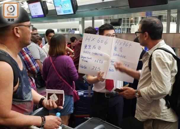 航空公司职员举着写有航班信息的纸牌提醒旅客图源：东网