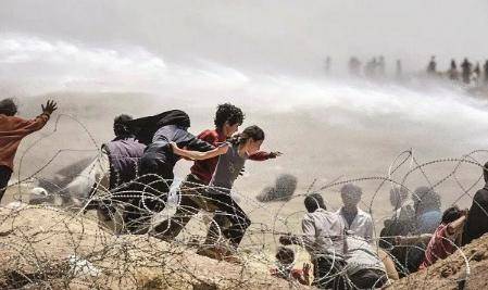 2015年，土耳其边境线，正在逃亡的叙利亚难民儿童躲避着土耳其士兵的高压水枪。