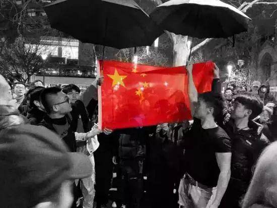 ▲中国留学生自发赶来，将乱港分子团团围住，他们高唱国歌，在雨夜中为国旗撑伞，手机/平板的屏幕上的国旗分外耀眼（图via网络）