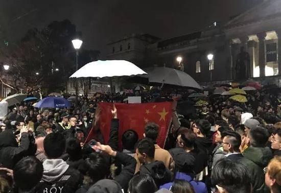 16日晚，澳大利亚墨尔本州立图书馆前，留学生们“雨中护旗”