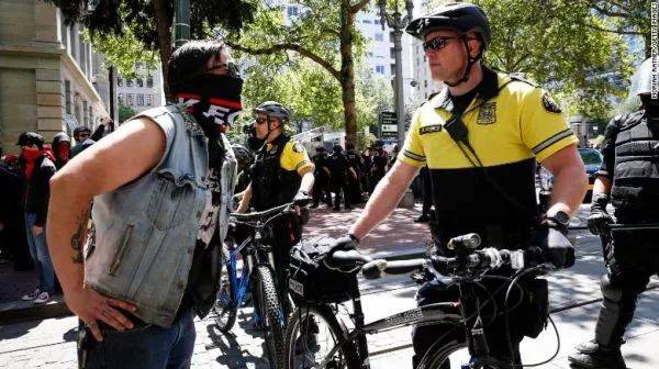 ▲6月29日，在美国波特兰，一名蒙面示威者与警察对峙。（CNN）