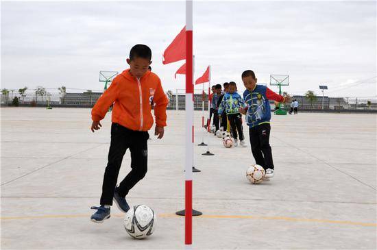 在武威市古浪县黄花滩生态移民区富民新村富民小学，足球兴趣小组的孩子们开展训练（8月22日摄）。新华社记者范培珅摄