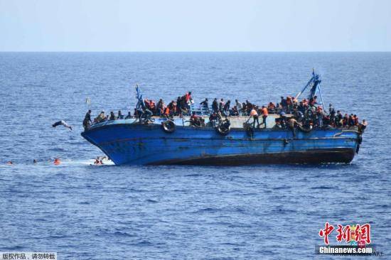 资料图：当地时间2016年5月25日，利比亚近海海域，一艘满载难民的船只即将倾覆，船上的难民纷纷跳海逃生。