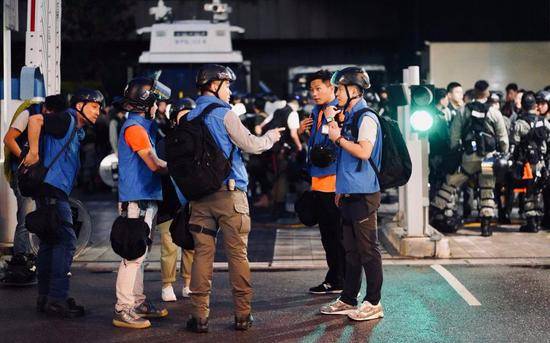 身穿蓝色背心的香港警方传媒联络队成员。