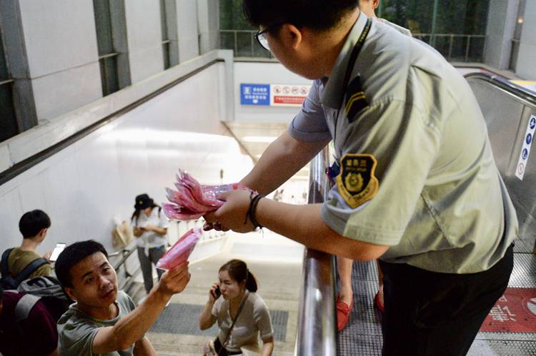 惠新西街南口地铁站，工作人员为出站乘客分发一次性雨衣。