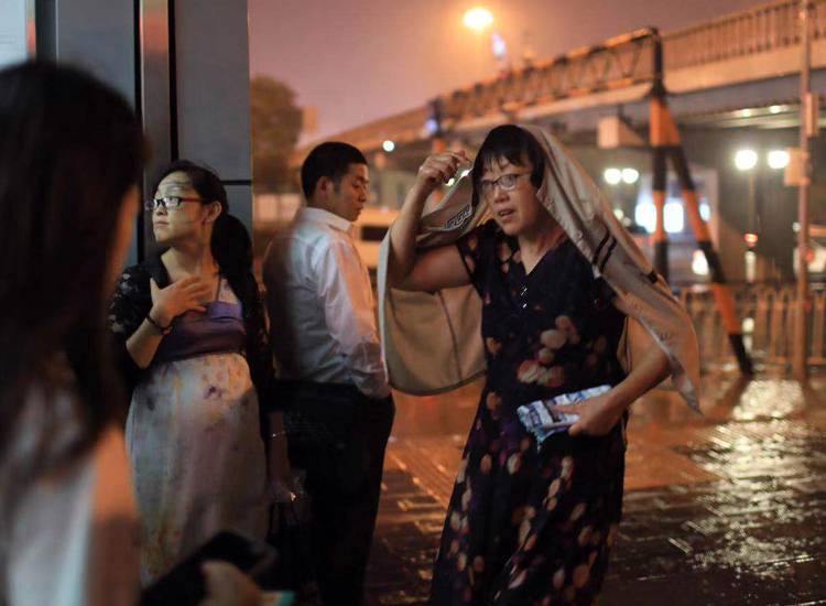 市民在地铁站出口处等雨停。