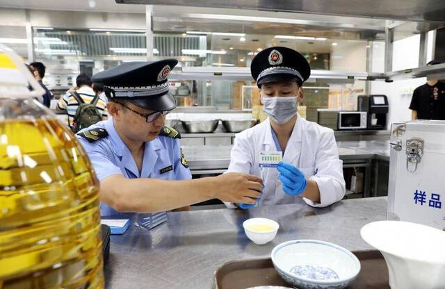 执法人员对餐厅使用的食用油进行现场检测。摄/通讯员何筱强