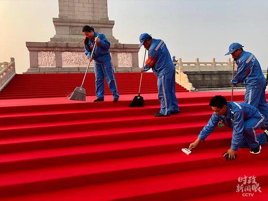 △早晨7点钟，环卫工人正在仔细打理人民英雄纪念碑台阶上新铺的红毯。（央视记者王威拍摄）