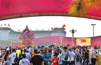 “十一”期间，天安门广场上的国庆花篮、大型景观雕塑“红飘带”成为游客拍照热门景点。新京报记者李木易摄