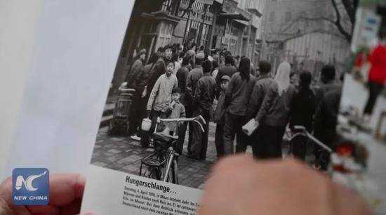 ▲库摩展示他1976年在中国拍摄的照片。（新华社报道截图）