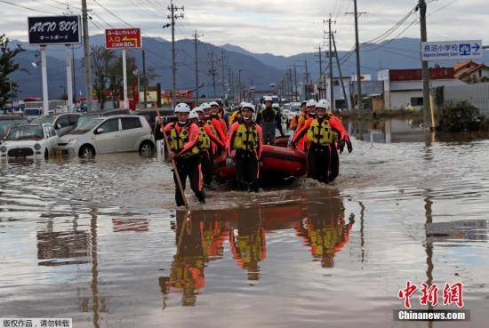 当地时间10月14日，台风“海贝思”造成日本长野县洪水泛滥，当地紧急开展救援行动。图为救援人员携带橡皮筏通过浅水区域。