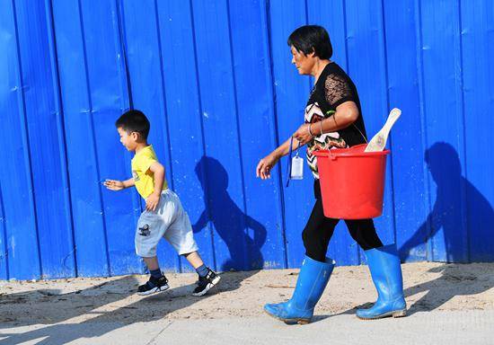 2019年6月25日，安徽省六安市舒城县晓天镇，陪读家长带着换洗衣物送孩子上学。一般送孩子到学校后，她们便去河边洗衣服。视觉中国供图