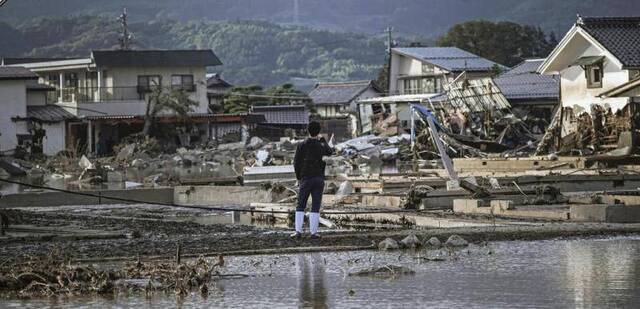 日本灾民站在因河川溃堤而遭受洪灾的住宅区前（《产经新闻》）