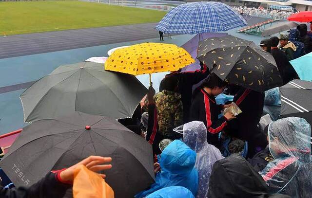 奥体中心看台，观众撑起五颜六色的雨伞。