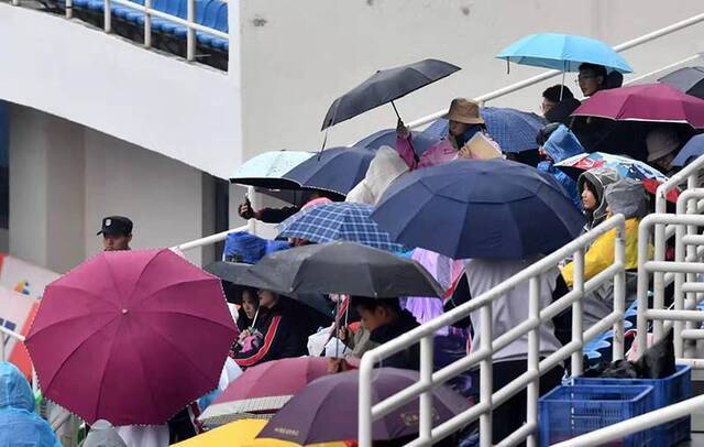 奥体中心看台，撑伞的观众在观看比赛。