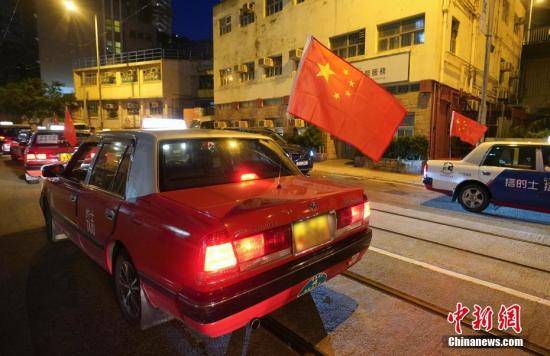 资料图：“守护香港大联盟”联同香港的士司机从业员总会发起“守护香港·风雨同舟”大行动，多辆出租车车身贴着海报，车尾悬挂五星红旗依次有序驶向主干道，呼吁社会反对暴力。中新社记者张炜摄