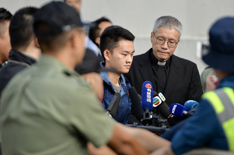 10月23日9时许，陈同佳在牧师陪同下走出香港新界壁屋惩戒所，表情严肃。新京报特派香港报道组摄