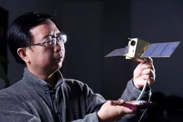 ▲资料图片：中国科学技术大学潘建伟教授在办公室内与“墨子号”量子卫星模型合影。（新华社）