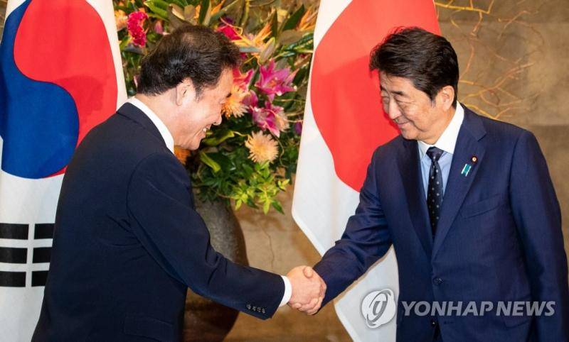  24日上午，韩国总理李洛渊与安倍晋三会面，面带笑容握手。（韩联社）