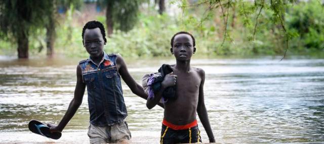 △联合国难民署丨在埃塞俄比亚马班县的难民营中，两个男孩在没过膝盖的洪水中行走。