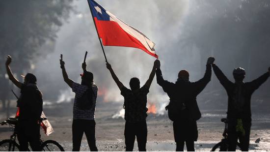 示威者在抗议不平等现象时举着智利国旗。图源：路透社