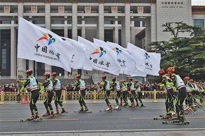 举着“中国冰雪”旗帜的轮滑队出发。