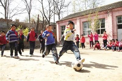 一所乡村学校的孩子们正在操场上踢足球。光明图片/视觉中国