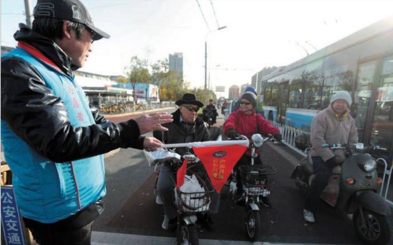 摩托骑士路口“站岗” 劝导骑车人别抢行