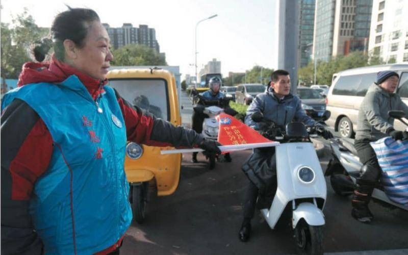 摩托骑士路口“站岗” 劝导骑车人别抢行