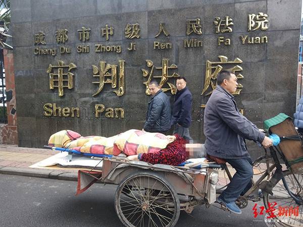 李伟躺在三轮车上，被载到成都市中级人民法院二审庭审现场。