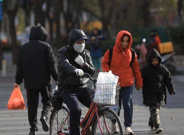 知春路，一位骑车人在寒风中扎紧领口。