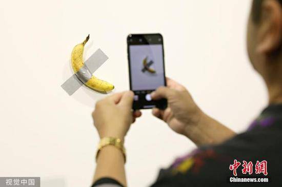 当地时间2019年12月6日，美国迈阿密海滩，意大利艺术家毛里卡特兰的作品《喜剧演员》在巴塞尔艺术展上展出。该作品由两部分组成：一段灰色胶带及一根香蕉。据媒体报道，之前的一根香蕉被人以12万美元的价格买走。图片来源：视觉中国