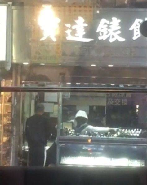 店内劫匪将手表收入胸前背包。视频截图