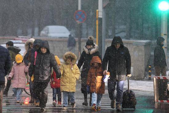 今天清晨，通州区芙蓉路，家长冒着雨雪陪着孩子前往学校。