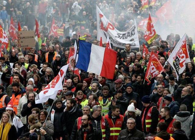 工会抗议者在里尔市举着CGT旗帜和法国国旗游行图片来源：美联社