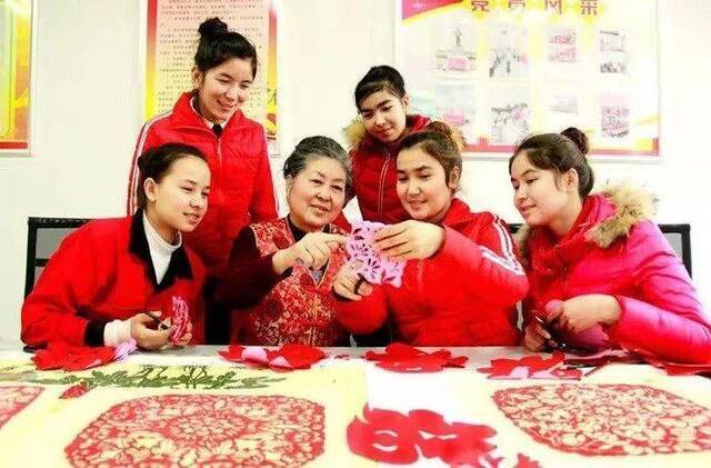 1月19日，安徽省工艺美术大师张秀珍向在皖务工的新疆和田皮山姑娘传授传统剪纸技艺。图源：安徽援疆网
