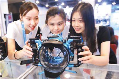 二〇一九年八月十六日，三位女孩在北京国际潜水展上被水下相机防水壳所吸引。陈晓根摄（人民视觉）