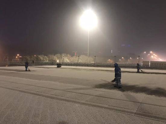 北京环卫集团工作人员在奥林匹克公园中心区内进行除雪作业。