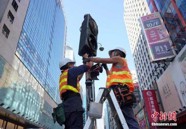 资料图：工程人员正在香港旺角弥敦道抢修早前被示威者破坏的交通信号灯。中新社记者张炜摄