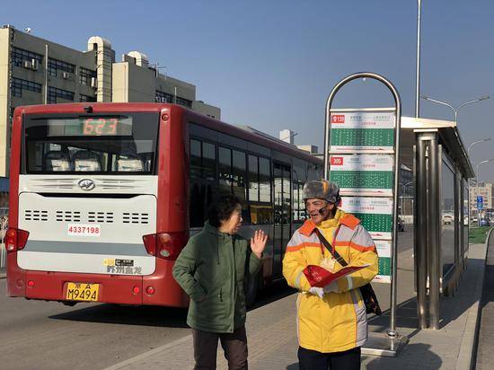 站前广场前的“上地东街中路”公交站，志愿者给旅客指路。新京报记者周依摄