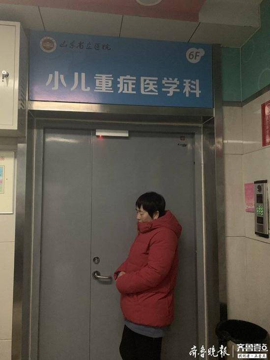 刘军芳（化名）倚在重症监护室大门前。记者李震摄